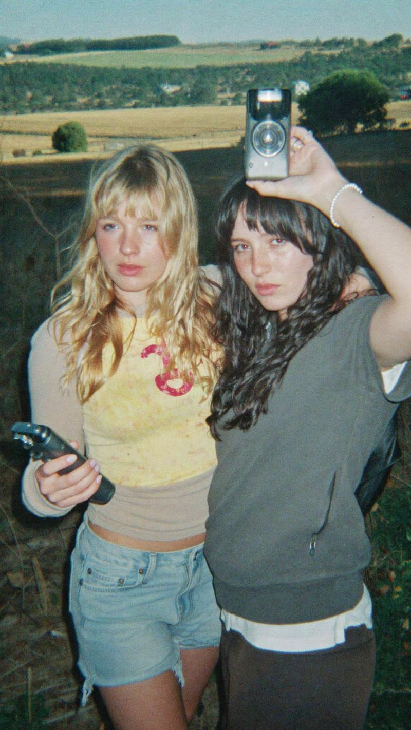 UGC style film photo of two friends holding cameras