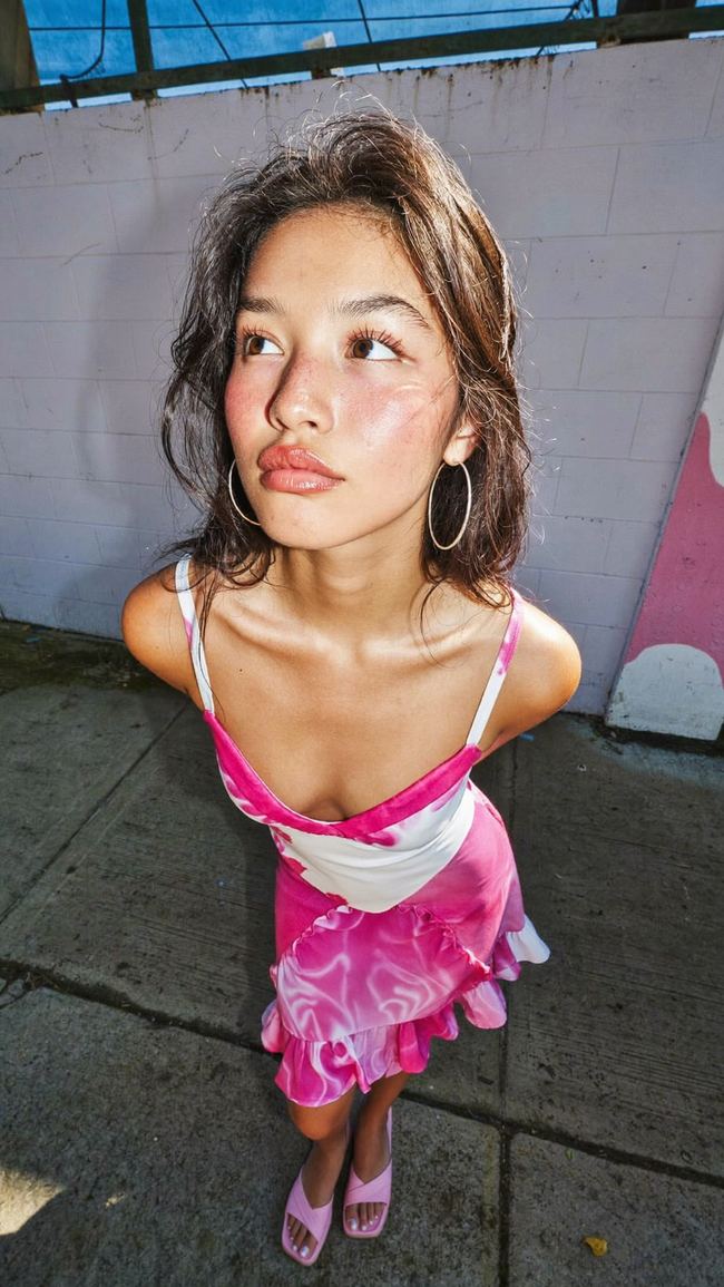 UGC style flash photo of a woman in a pink dress on the street