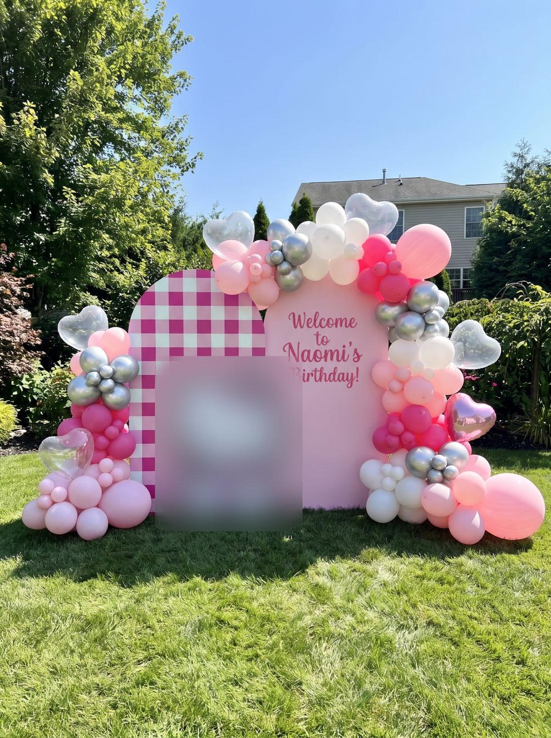 Pink balloon arch and gingham backdrop for a birthday