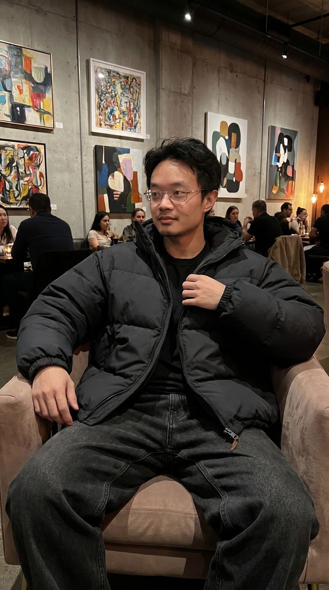 UGC style photo of a man in a puffer jacket at an art gallery cafe