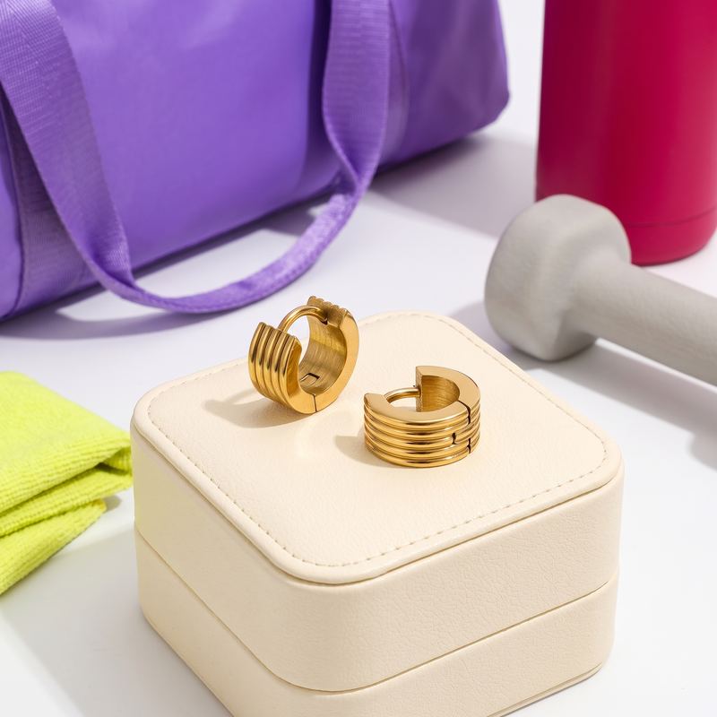 Ribbed gold huggie earrings on a jewelry box