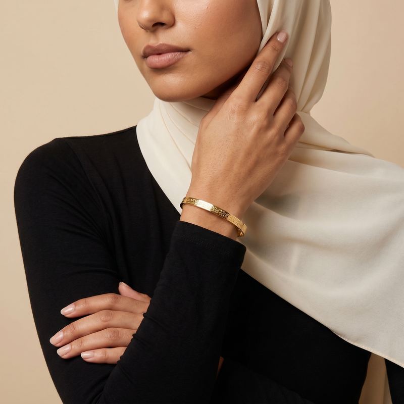 Engraved gold bangle worn by a model in a headscarf